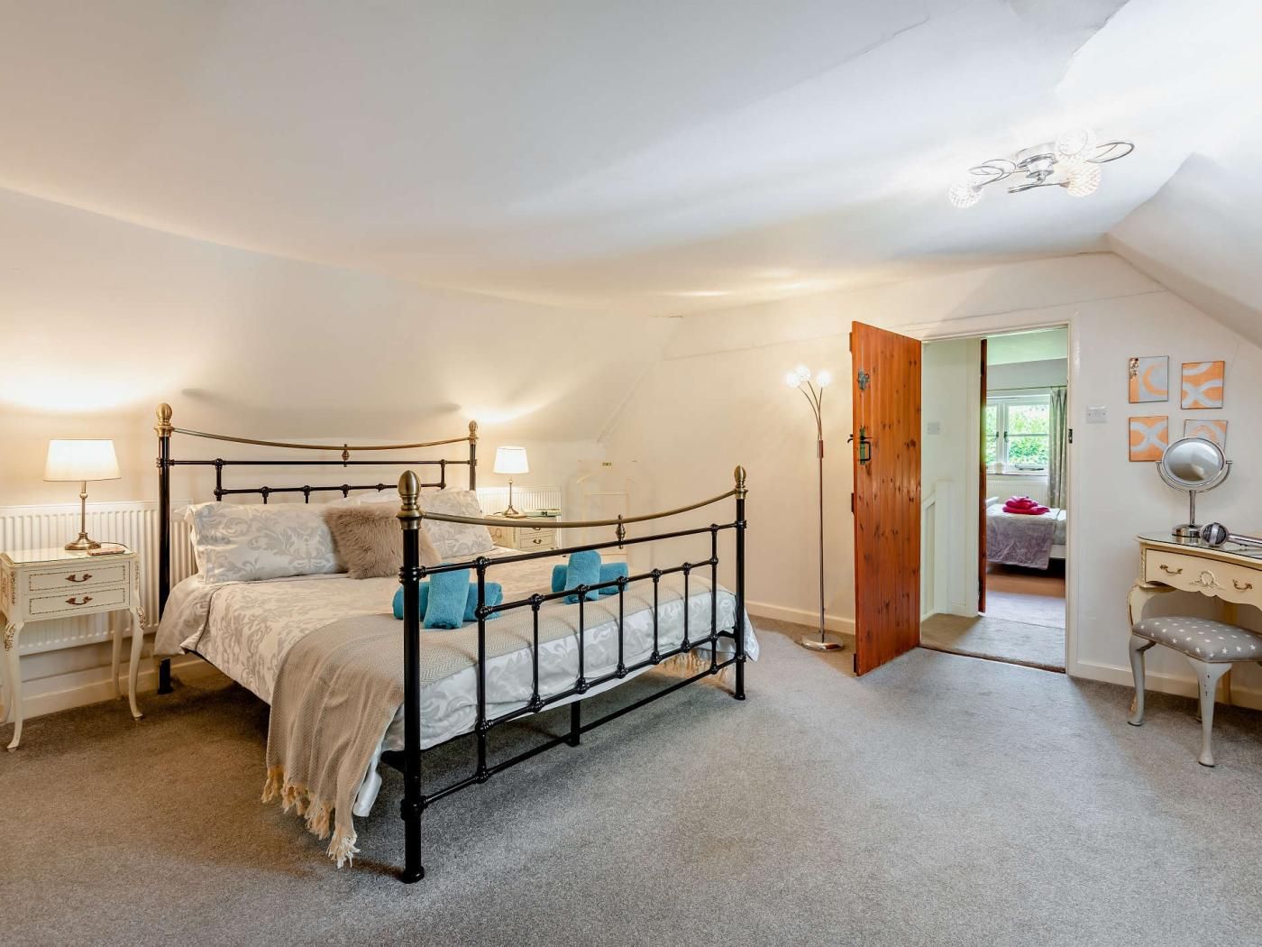 Ein Schlafzimmer mit einem Himmelbett, Nachttischen, einer Holztür und einem kleinen Schreibtisch mit Stuhl.