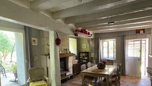 A cozy living room with a fireplace, a dining table, and a sofa. - Charming Vacation Rental in Touraine (Chançay)