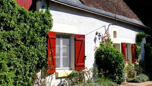 A traditional house with a sloped roof, red shutters, and a gravel driveway. - Charming Vacation Rental in Touraine (Chançay)