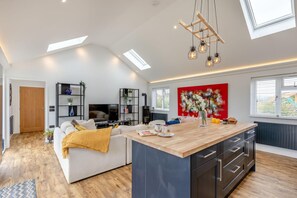 A modern kitchen with a central island, built-in appliances, and a dining area with a sofa.