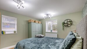 Un dormitorio con una cama, dos ventanas, un armario y una lámpara en el techo.