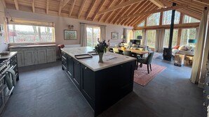 Eine geräumige Küche mit einer großen Kochinsel, Holzbalken und großen Fenstern.