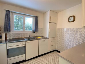 A compact kitchen with a window, a sink, a stove, and a refrigerator. - Haus Montana 3/7 Appartement/Fewo,   5-Bettwohnung by Interhome (Lenzerheide)