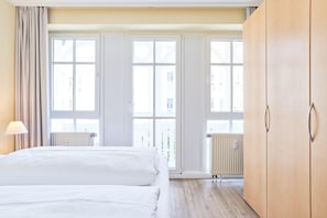 Ein Hotelzimmer mit einem Bett, einem Holzschrank und großen Fenstern.