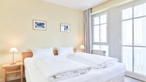 Ett hotellrum med en stor säng, två sängbord, ett fönster och två inramade tavlor på väggen.