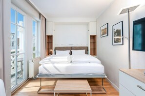 Une chambre moderne avec un lit, des tables de chevet, un bureau et une vue sur la ville.
