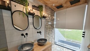 A modern bathroom with two sinks, large mirrors, and a view of a green lawn. - 5 Bed in Blyth (oc-t34727) (Blyth)