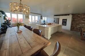 A spacious kitchen with a wooden dining table, white cabinetry, and a stone accent wall. - 5 Bed in Blyth (oc-t34727) (Blyth)