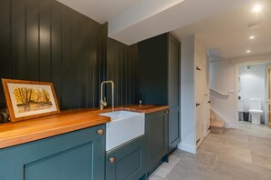 A modern kitchen with dark cabinetry, a wooden countertop, and a sink. - 3 Bed in Bispham (oc-f34979) (Bispham)