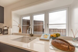 A kitchen with a large window, a sink, a coffee maker, a book, and a loaf of bread. - 3 Bed in Bispham (oc-f34979) (Bispham)