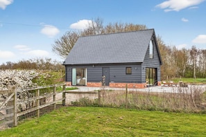 A modern house with a sloped roof, a large glass door entrance, and a fenced yard.