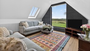 Habitació d'estil loft amb una finestra gran, un sofà, una taula de cafè i una televisió.