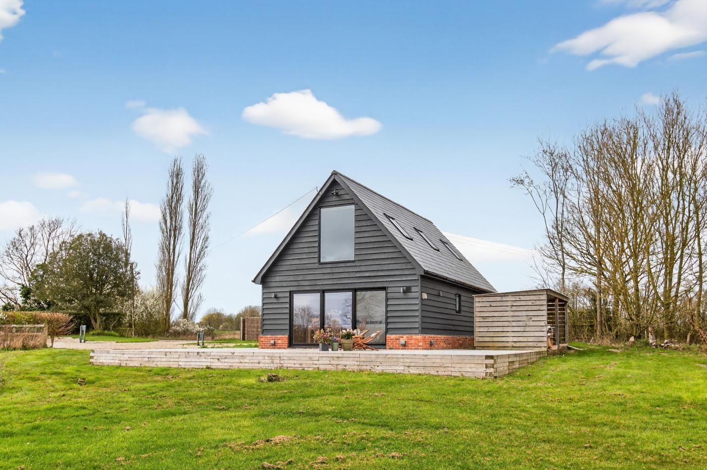 Une maison moderne dotée d’une grande fenêtre, d’un toit en pente et de fondations en briques.