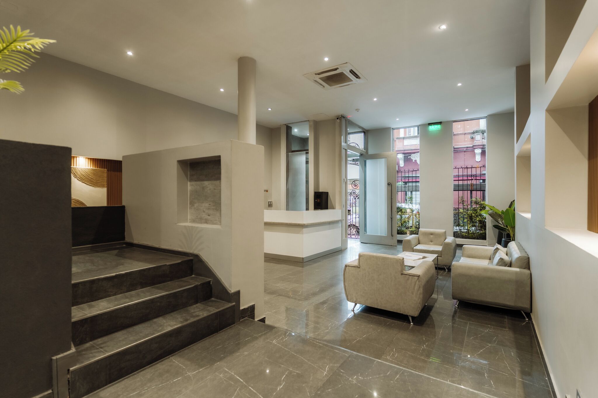 Una hall moderna con reception, area salotto e una scala.