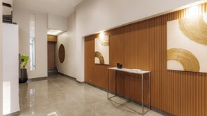 A modern reception area with a wooden panel wall, a reception desk, and a potted plant. - Hestia en Cochabamba Boutique (Buenos Aires)