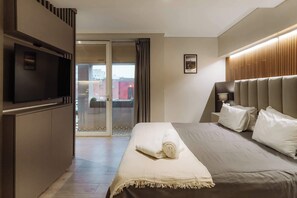Et hotelværelse med seng, fjernsyn, en skydedør til en balkon og et billede i ramme på væggen.