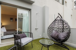 Una habitación con cama, una silla colgante, una mesa de vidrio y una ducha.