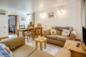 A living room with a sofa, a dining table with chairs, a TV, and a remote control. - 2 Bed in Risca (oc-b35977) (Risca)