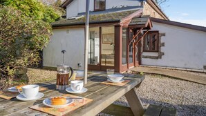Ein Holztisch für ein Picknick mit Kaffeekanne, Tassen und Gebäck.