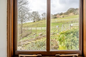 A view through a window with a wooden frame, featuring a grassy field, a wooden staircase, and a metal fence. - 2 Bed in Risca (oc-b35977) (Risca)