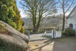 A gated entrance with a paved path leading to a building, surrounded by trees and shrubs. - 2 Bed in Risca (oc-b35977) (Risca)