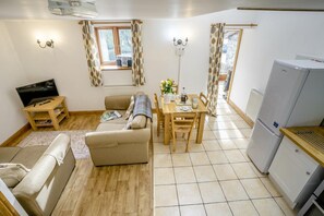 Ein gemütlicher Wohnbereich mit Sofa, Esstisch, Fernseher und Kühlschrank.