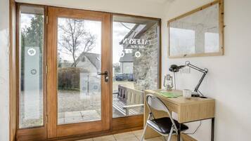 A room with a wooden desk, a chair, a lamp, and a map on the wall.