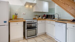 Una cocina compacta con estufa, horno, microondas y lavavajillas.