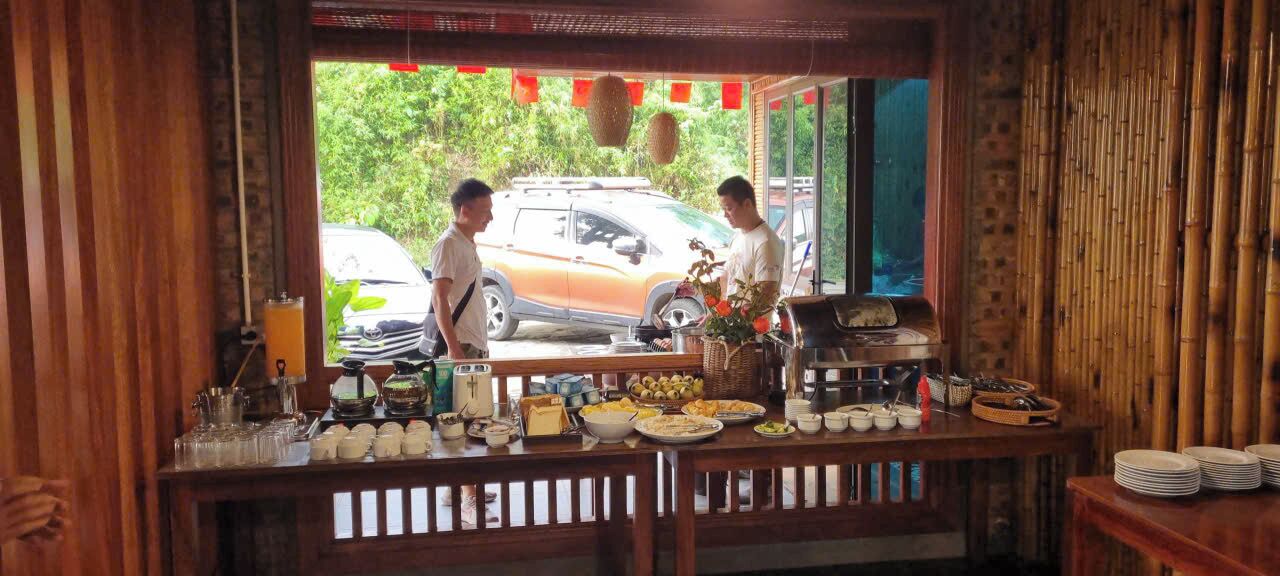 Un restaurant avec un intérieur en bois, un comptoir où sont exposés des plats, et une voiture visible à travers la fenêtre.