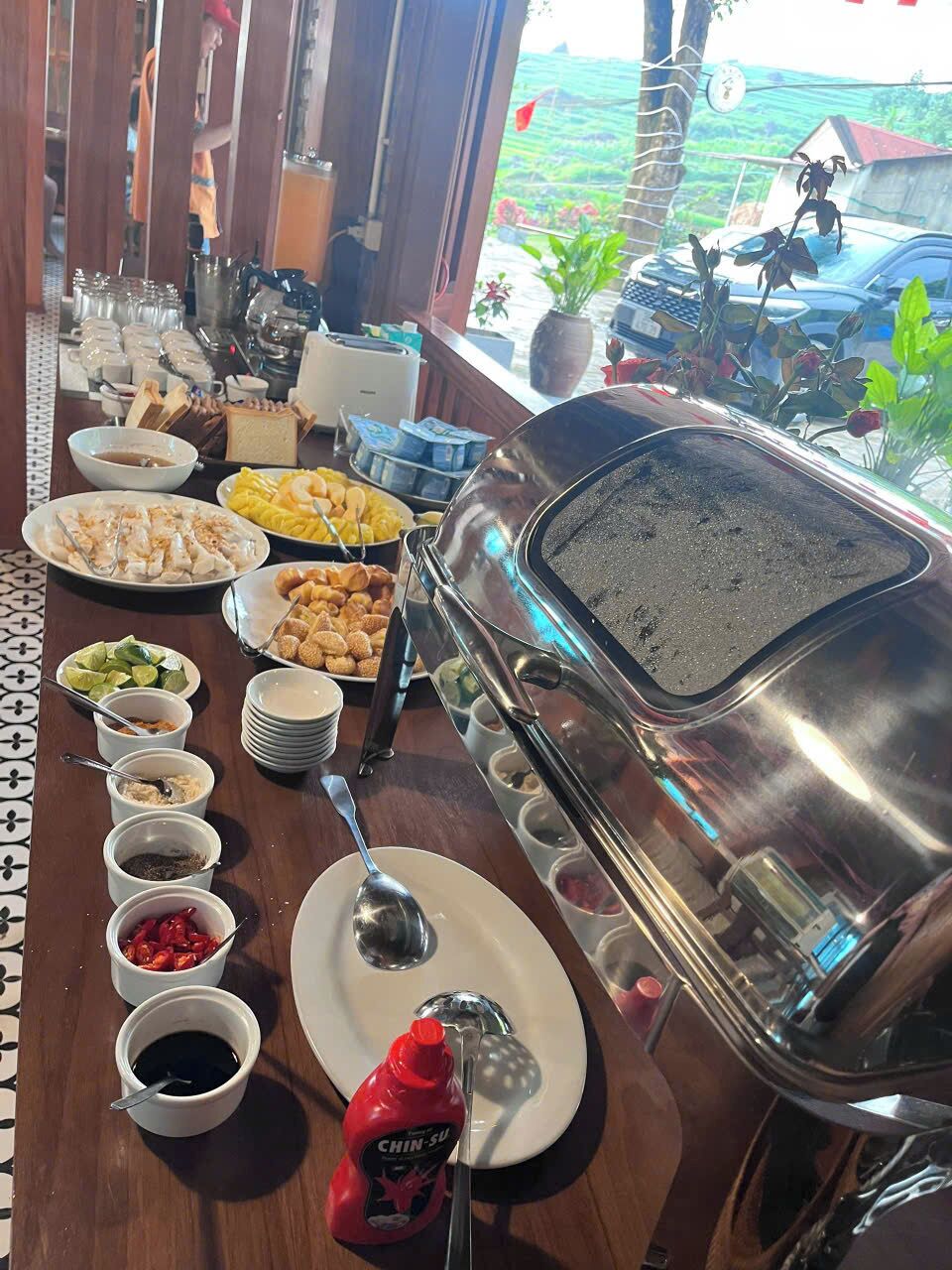 A buffet setup with various dishes, condiments, and a grill.