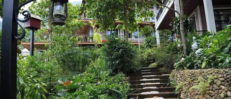 A staircase surrounded by lush greenery, leading to a building with multiple balconies.