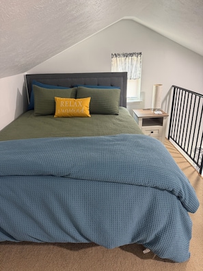 A bedroom with a bed, pillows, a nightstand, a lamp, and a window with curtains. - Cozy Creek Retreat - Spiral staircase,AC,high speed WiFi (Waterford)