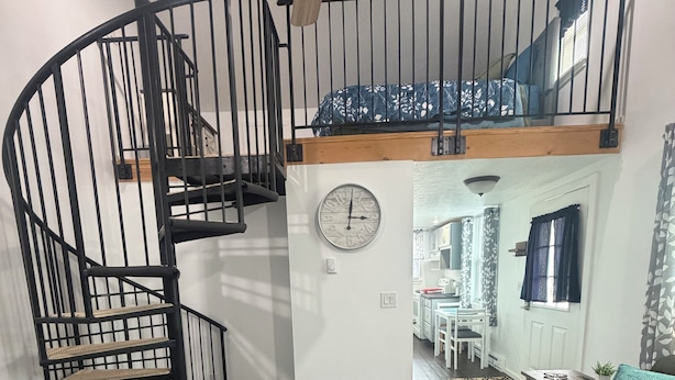 A modern interior with a spiral staircase, a wooden ceiling fan, a dining area, and a living room with a sofa and a rug. - Cozy Creek Retreat - Spiral staircase,AC,high speed WiFi (Waterford)