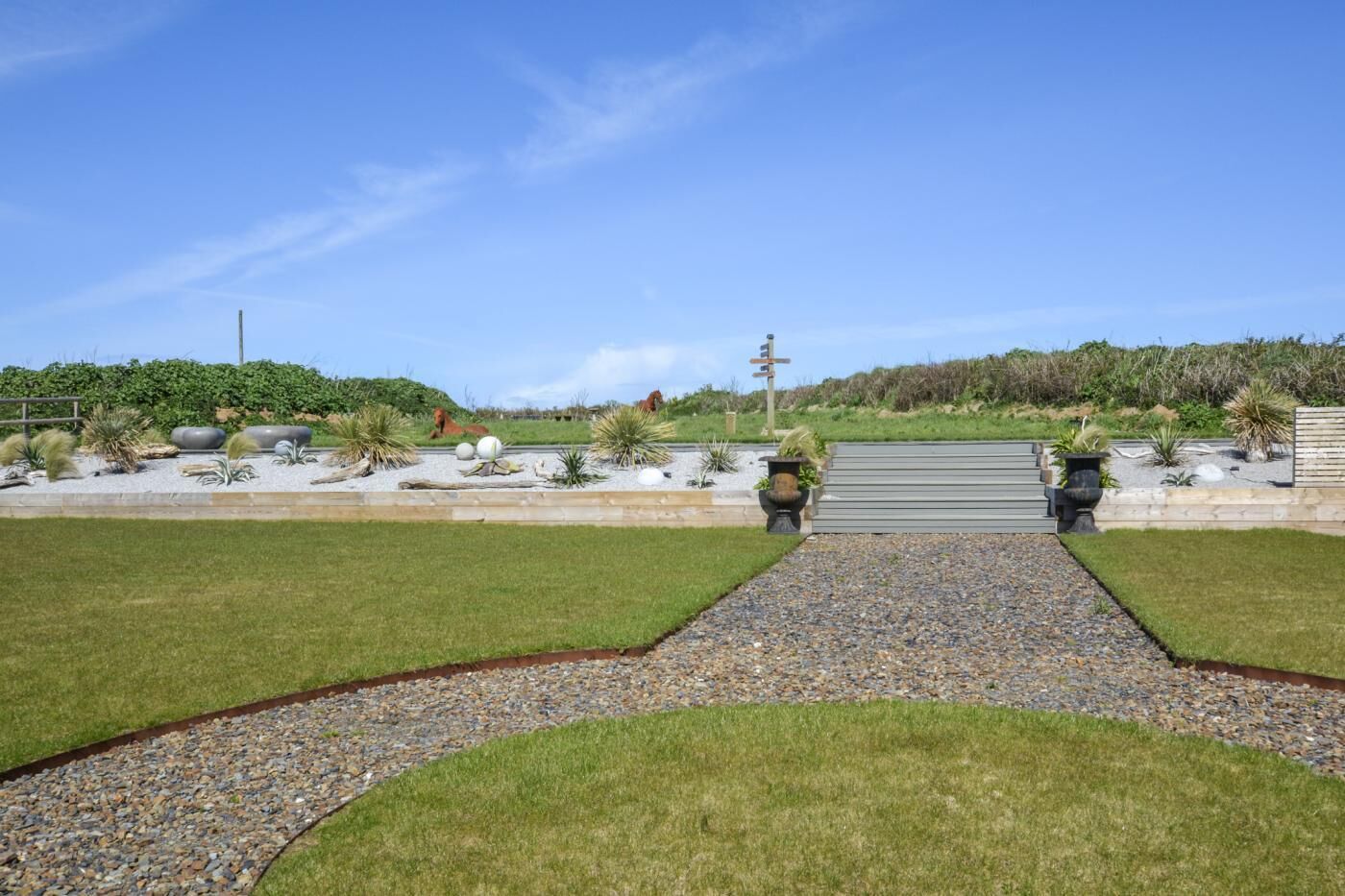 A landscaped garden with a gravel path, grass, and various plants.