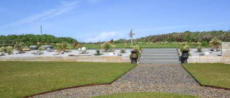 A landscaped garden with a gravel path, grass, and various plants.