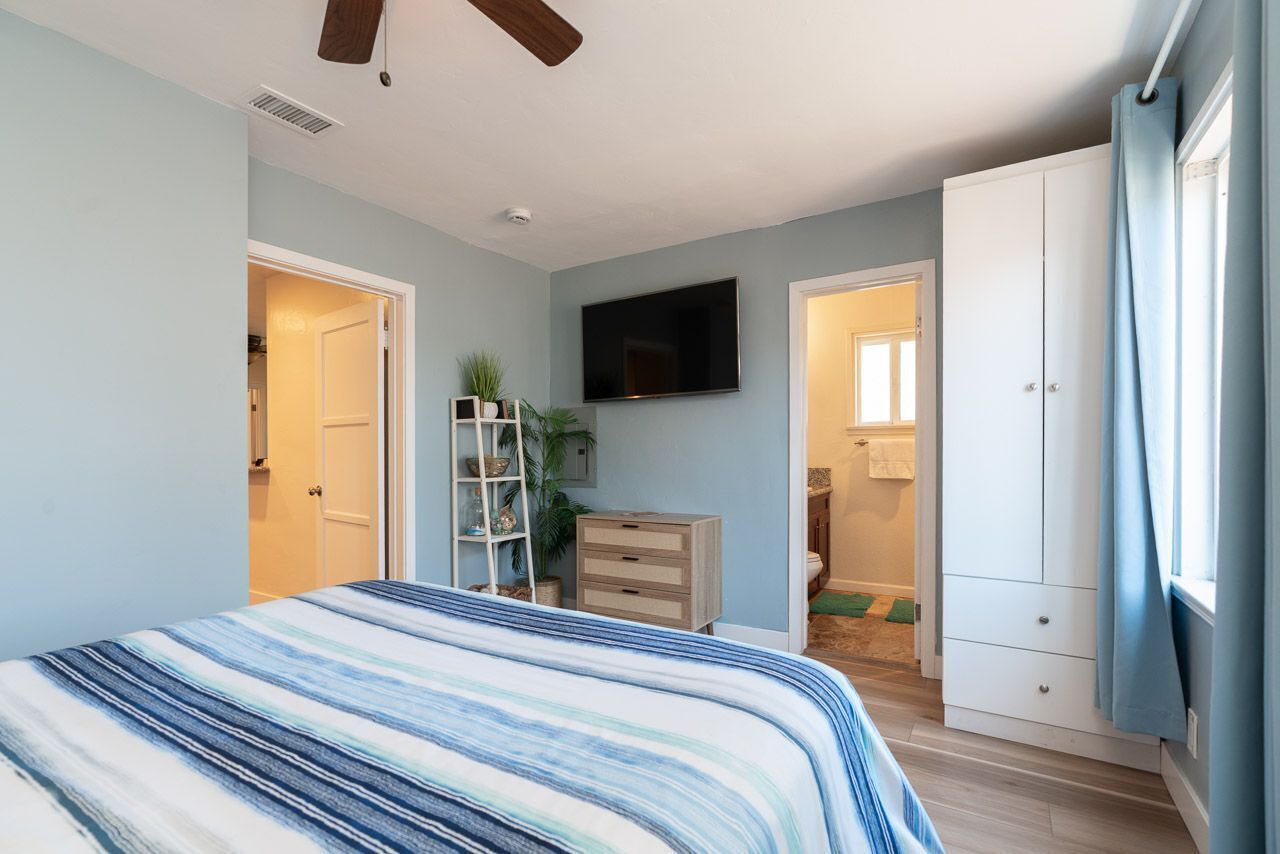 A bedroom with a bed, a TV, a wardrobe, and a bathroom visible through an open door.