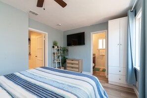 A bedroom with a bed, a TV, a wardrobe, and a bathroom visible through an open door. - Chula Vista Retreat Near Gaylord Pacific | 3BR/2BA (Chula Vista)