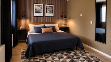 A hotel room with a bed, geometric-patterned rug, wall-mounted artwork, and a large mirror.