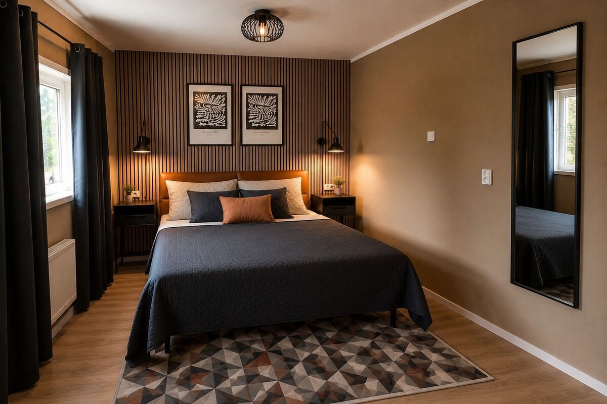 Una camera da letto con un letto grande, due comodini, un tappeto dal motivo geometrico e uno specchio fissato alla parete.