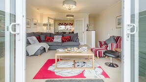 Ein Wohnzimmer mit grauem Sofa, einem gestreiften Sessel, einem Couchtisch und einem roten Teppich.