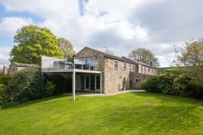 Una casa in pietra con un'estensione moderna e un balcone in vetro.