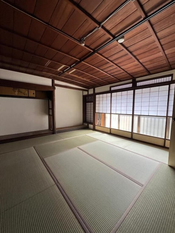 Una habitación tradicional japonesa con suelo de tatami, vigas de madera y puertas correderas.