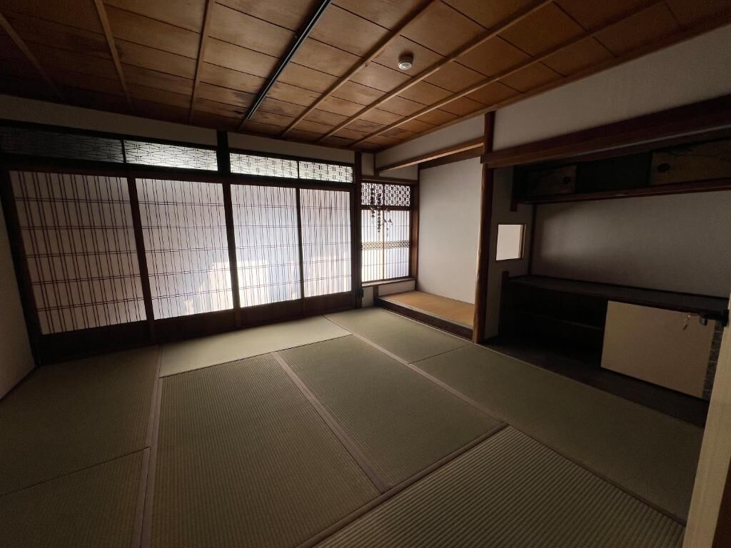 Una habitación japonesa tradicional con suelo de tatami, puertas correderas y techo de madera bajo.