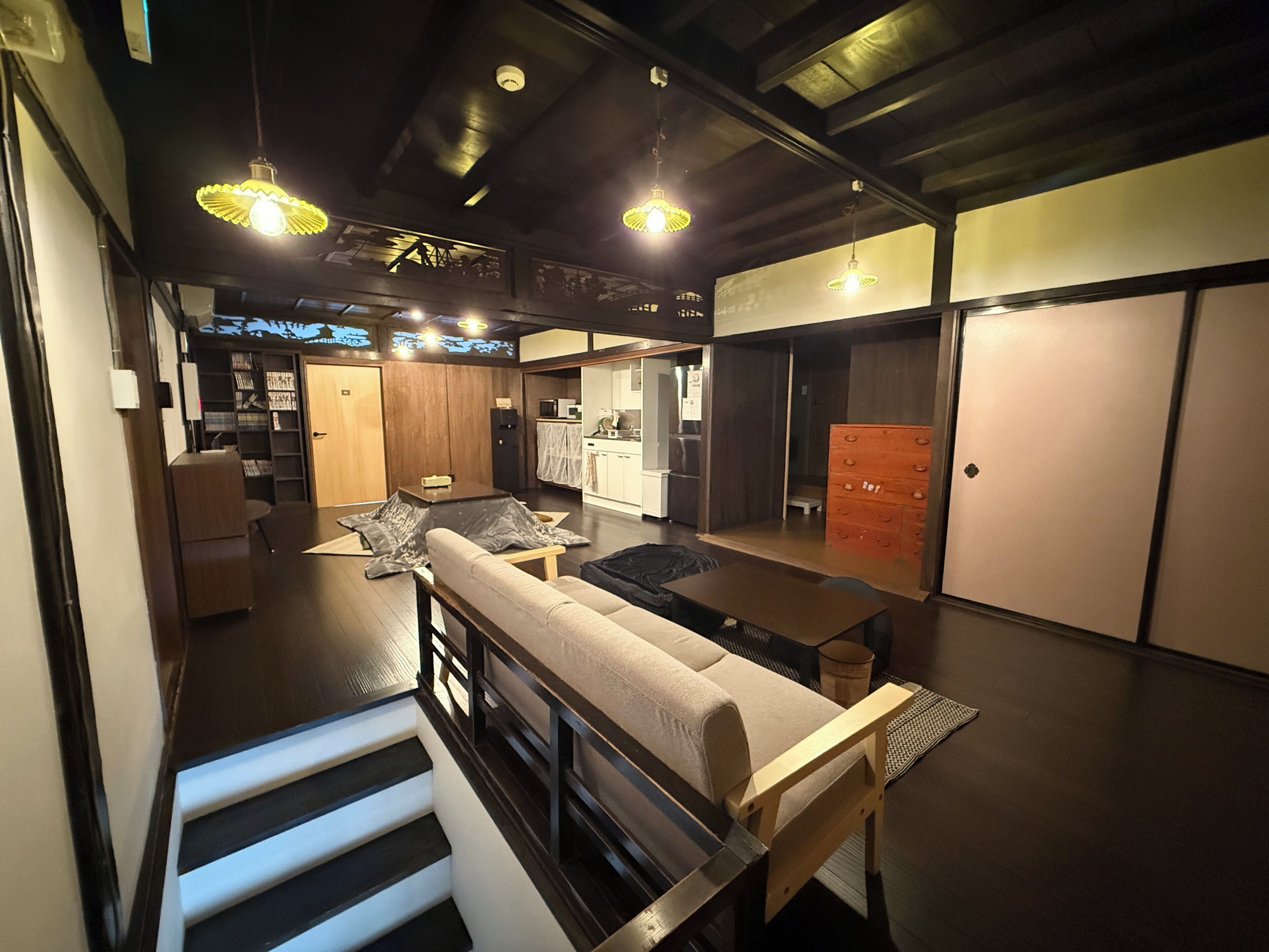 Een modern interieur met een trap, een bank, een eettafel en een keukenhoek.