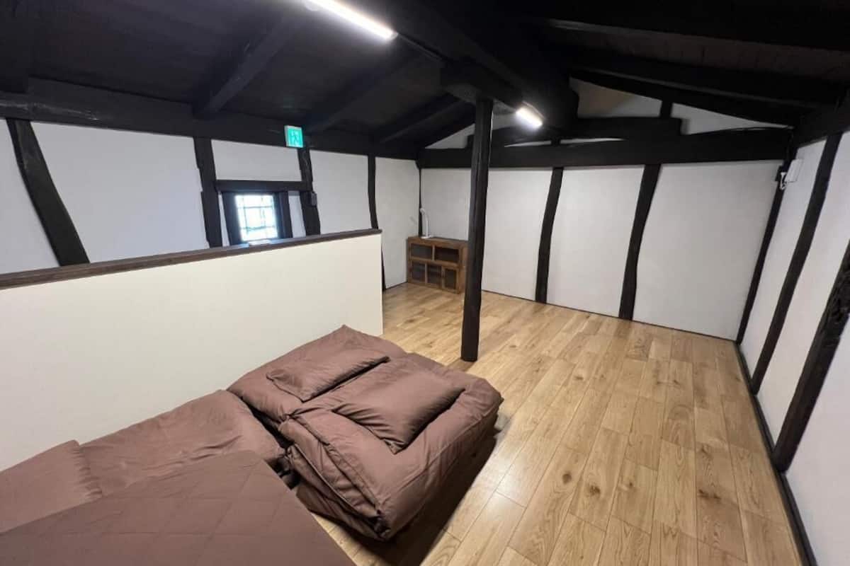 A room with a bed, wooden flooring, and exposed beams.