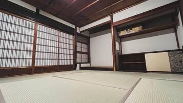 A traditional Japanese room with tatami flooring, sliding doors, and a low wooden ceiling.