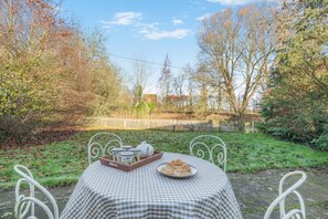 An outdoor dining area with a checkered tablecloth, a tray with teapots and cups, and a plate of pastries. - 2 Bed in Caenby (oc-o35799) (Caenby)