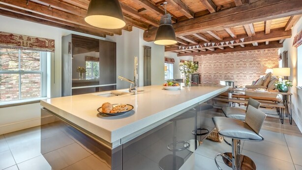Cozinha moderna com uma ilha grande, luminárias pendentes e parede de tijolos.