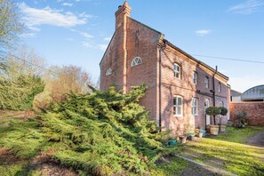 A brick building with a prominent tower, surrounded by greenery and a clear sky. - 2 Bed in Caenby (oc-o35799) (Caenby)