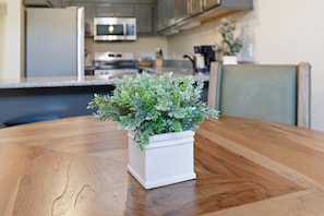 A potted plant on a wooden table in a kitchen with cabinets and appliances in the background. - Spacious 3-bedroom condo with River and Mountain Views (Sevierville)